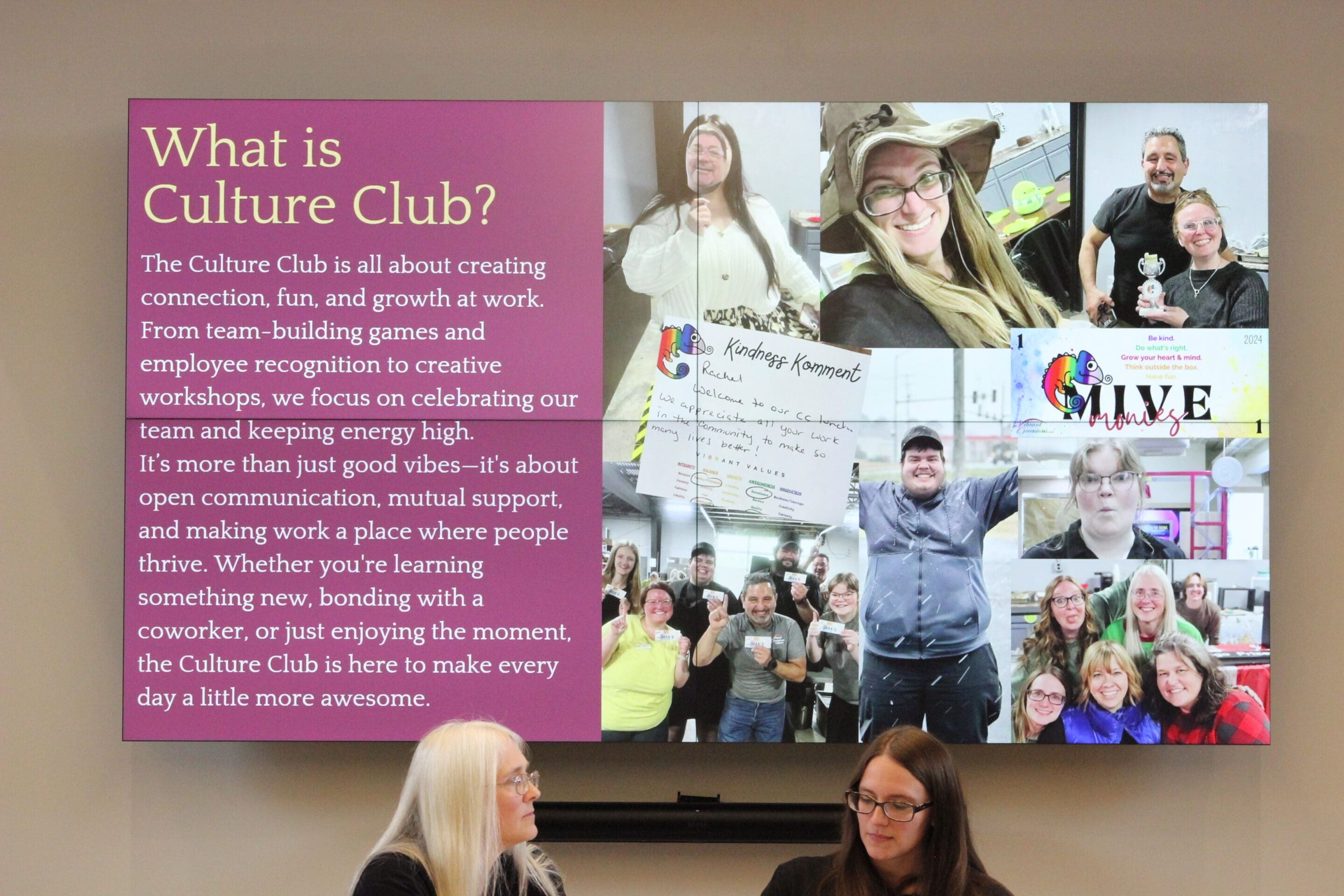 A display screen reads What is Culture Club? with a description and a collage of smiling people at events. Below, two women sit and talk at a table, facing the audience.